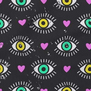 以下が含まれることがあります： 黄色と緑の瞳とピンクのハートを持つ、スタイリッシュな目の繰り返しパターンが描かれた黒い背景。水滴が表面にあるかのように、パターンはわずかにぼやけています。