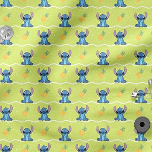 Pu&ograve; includere: Un tessuto verde con un motivo ripetuto di personaggi blu Stitch e ananas gialli. Lo sfondo ha un motivo di linee ondulate bianche e macchie bianche.