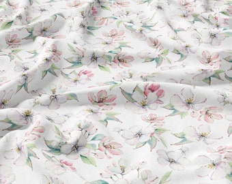 May include: White fabric with a delicate floral pattern featuring pink and white blossoms and green leaves. The fabric is wrinkled and has a soft, watercolor-like appearance.
