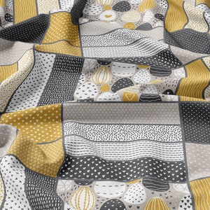 May include: A fabric with a patchwork design featuring geometric shapes and abstract patterns in shades of gray, white, and yellow.