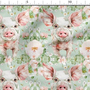 May include: A seamless pattern featuring watercolor illustrations of pink piglets with white spots, surrounded by green leaves and pink and white flowers on a light green background.