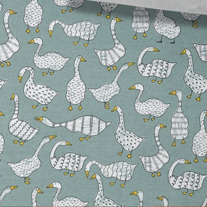May include: A teal blue fabric with a repeating pattern of white geese. The geese have different patterns on their bodies, including dots, stripes, and wavy lines. The geese have yellow beaks and feet.