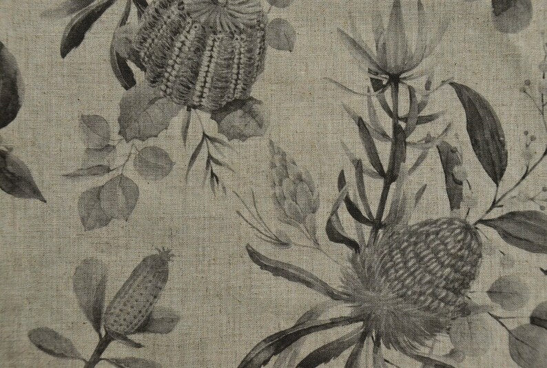 May include: A beige linen fabric with a black and white floral print featuring stylized flowers and leaves. The print is reminiscent of Australian flora.