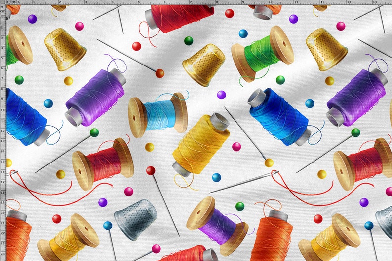 Op de afbeelding: Een witte achtergrond met een herhalend patroon van kleurrijke spoelen garen, vingerhoeden en spelden. De spoelen garen zijn in verschillende kleuren, waaronder rood, blauw, groen, geel en paars. De vingerhoeden zijn zilver en goud. De spelden zijn wit met rode koppen.