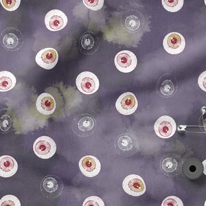 May include: Purple fabric with a repeating pattern of white eyeballs with red pupils.  There are safety pins and a metal gear on the fabric.