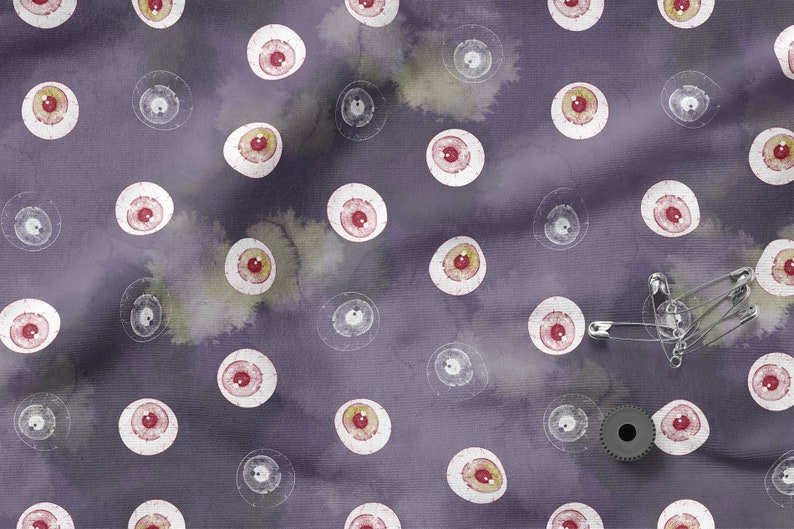 May include: Purple fabric with a repeating pattern of white eyeballs with red pupils.  There are safety pins and a metal gear on the fabric.
