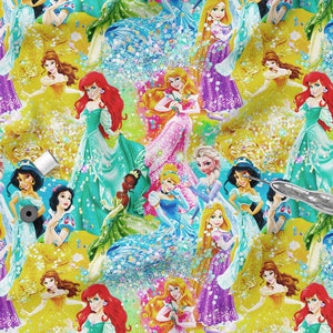 Op de afbeelding: Een kleurrijke stofdruk met verschillende Disney-prinsessen in hun iconische jurken. De prinsessen zijn omringd door glitter en glans, wat een magisch en fantasierijk ontwerp creëert.