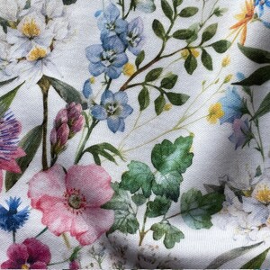 May include: White fabric with a floral print featuring pink, blue, and purple flowers. The fabric has a textured, linen-like appearance.
