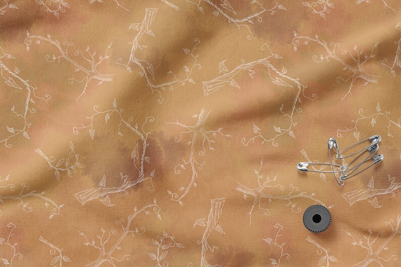 May include: A brown fabric with a white vine pattern. There are safety pins and a spool of thread on the fabric.