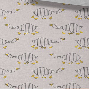 May include: A gray and white fabric with a repeating pattern of geese and goslings. The geese are striped and the goslings are yellow. The fabric is 50 cm (19.70 inches) wide.