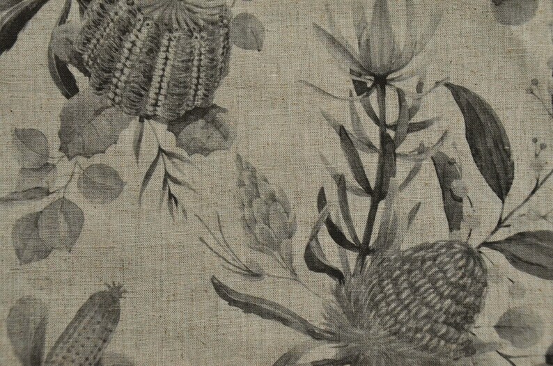 May include: A beige linen fabric with a black and white floral print. The print features stylized flowers and leaves.