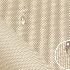 Pode incluir: Close-up de um tecido bege com trama texturizada. Gotas de água são mostradas na superfície do tecido, demonstrando suas propriedades de resistência à água.