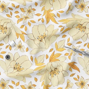 K&ouml;nnte beinhalten: Wei&szlig;er Stoff mit einem sich wiederholenden Blumenmuster in Creme und Gelb. Das Design umfasst gro&szlig;e, pfingstrosenartige Bl&uuml;ten, kleinere Bl&uuml;ten und goldene Bl&auml;tter. N&auml;hutensilien, darunter Garnrollen und ein Nahttrenner, sind auf dem Stoff verstreut.