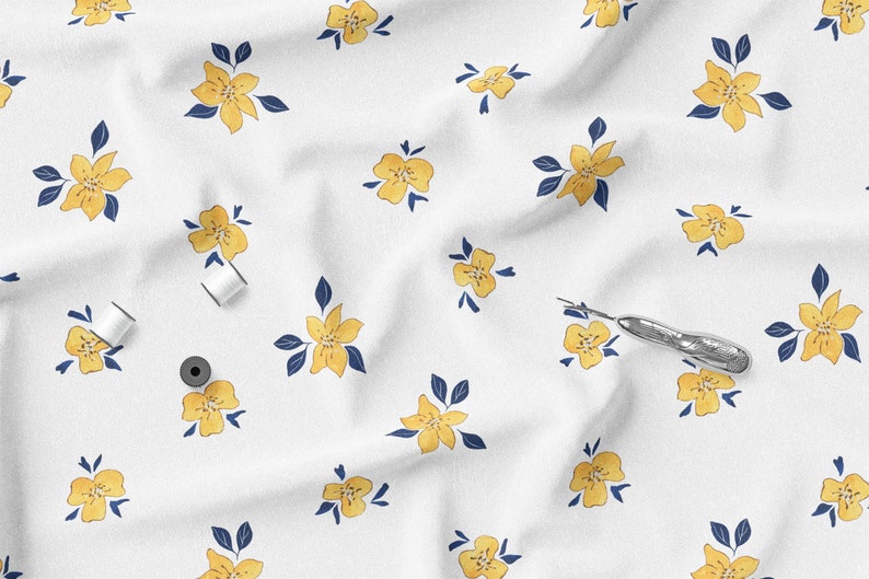 K&ouml;nnte beinhalten: Wei&szlig;er Stoff mit einem sich wiederholenden Muster aus gelben Blumen und marineblauen Bl&auml;ttern. Zwei Spulen wei&szlig;en Fadens und ein silberner Nahttrenner sind ebenfalls zu sehen. Geeignet f&uuml;r N&auml;h- oder Bastelprojekte.