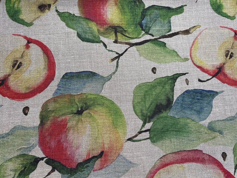 May include: A watercolor pattern of red apples with green leaves on a light gray linen background.