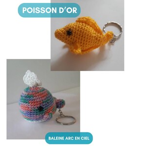 K&ouml;nnte beinhalten: Zwei geh&auml;kelte Schl&uuml;sselanh&auml;nger, einer ist ein gelber Fisch mit dem Text "POISSON D'OR" und der andere ist ein mehrfarbiger Wal mit dem Text "BALEINE ARC EN CIEL".