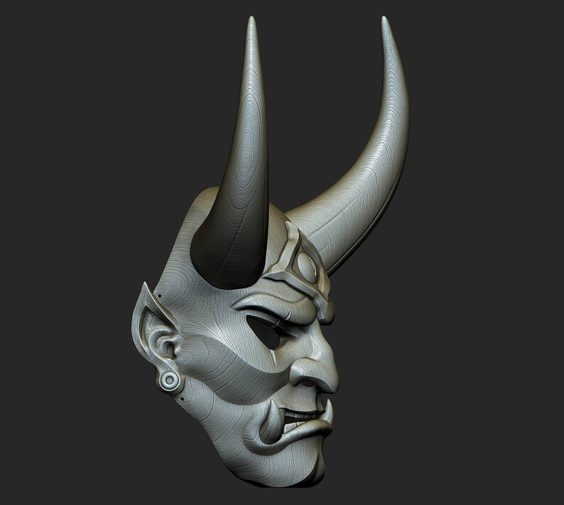 May include: A grey, detailed, wooden mask with horns and a fierce expression. The mask has a textured surface and appears to be hand-carved.