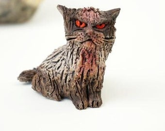 May include: A ceramic cat figurine with a distressed, textured finish. The cat has red eyes and a menacing expression.