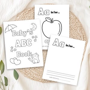 Op de afbeelding: Zwart-witte printbare kleurplaten voor een baby-ABC-boek. De pagina's bevatten een appel, een maan, een kat en een paraplu. De tekst op de pagina's luidt "Baby's ABC Book" en "Aa is voor..."