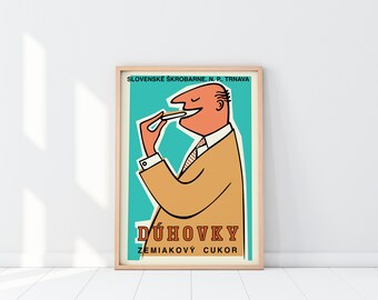 May include: A vintage poster advertising "Dúhovky Zemíakový Cukor" (Rainbow Potato Sugar) with a cartoon illustration of a man eating a piece of the product. The poster is in a wooden frame and has a blue background with white and orange text.