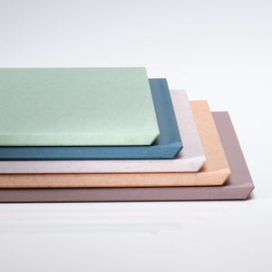 May include: A stack of rectangular serving trays in various pastel colors, including mint green, blue, pink, peach, and mauve. Each tray has a speckled texture and a slightly raised edge. The trays are stacked on top of each other.