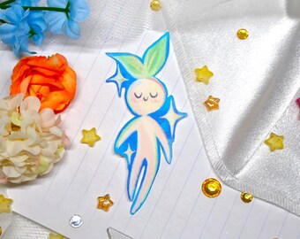 May include: A flat, die-cut sticker featuring a stylized, pale pink humanoid figure with a smiling face and closed eyes. The figure has green leaf-like ears and is outlined in vibrant blue, accented by four-pointed blue star shapes.