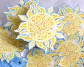 May include: A collection of circular stickers featuring a stylized yellow sun design with intricate orange patterns, sharp flame-like rays, and a light blue border. Each sun graphic includes small white star-shaped accents.