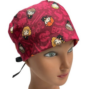 May include: A red surgical scrub hat with a print of Harry Potter characters and symbols. The hat has black ties.