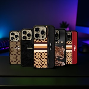 Puede incluir: Una colección de fundas para teléfonos Coach con varios diseños. Las fundas presentan el logotipo de Coach, texturas de cuero y patrones en marrón, negro y rojo. Algunas fundas tienen un estampado de leopardo o un diseño a rayas. Las fundas se muestran sobre una superficie negra.