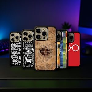 Könnte beinhalten: Eine Sammlung schwarzer Handyhüllen mit verschiedenen Designs. Eine Hülle zeigt eine Karte, eine andere eine Brille, und andere zeigen Text und Grafiken. Die Hüllen sind auf einer dunklen Oberfläche angeordnet, mit einem unscharfen Hintergrund.