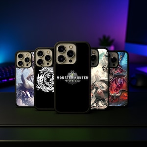 May include: A collection of black phone cases with various designs. One case features the text "MONSTER HUNTER WORLD" in white. Other cases display detailed illustrations of creatures and symbols. The cases are arranged on a dark surface.