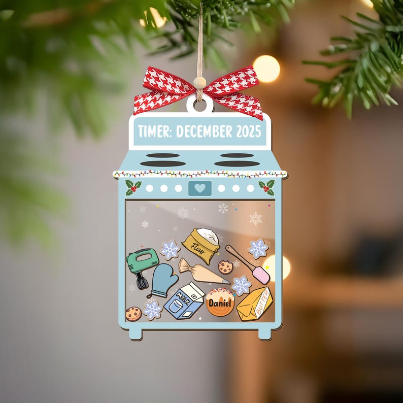 May include: A light blue oven-shaped Christmas ornament with a red and white bow. The ornament features the text "TIMER: DECEMBER 2025" and illustrations of baking supplies, including flour, milk, and butter. A personalized name is also included.