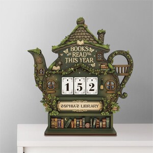 May include: A whimsical, green teapot-shaped bookshelf and book counter. The counter reads "BOOKS READ THIS YEAR" and "152". The bottom shelf displays miniature books. The sign reads "SOPHIA'S LIBRARY".