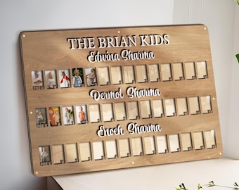 Può includere: Una bacheca di foto di famiglia in legno con la scritta "THE BRIAN KIDS" e tre nomi di famiglia. La bacheca ha più slot per foto con la parola "PREK" visibile nell'angolo di alcune foto.