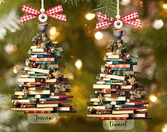 May include: Two Christmas tree ornaments shaped like a stack of books with a coffee cup on top. The ornaments are decorated with red and white checkered ribbon. The ornaments are personalized with the names "Jessica" and "Daniel".