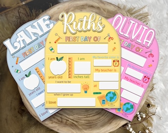 Puede incluir: Tres carteles coloridos para el primer día de escuela con fondo amarillo, azul y rosa. Cada cartel tiene un nombre en la parte superior, "Lane", "Ruth's" y "Olivia". Los carteles tienen espacios para completar información sobre la edad, la altura, el color favorito y el maestro del niño.
