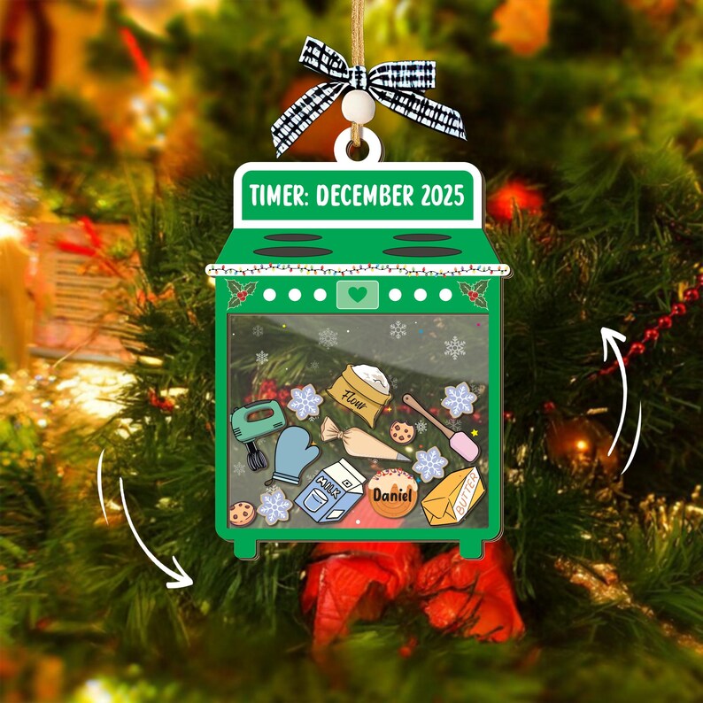 May include: A green oven-shaped Christmas ornament with the text "TIMER: DECEMBER 2025". The ornament features baking-themed illustrations inside, including a mixer, flour, and cookies. It is decorated with a black and white bow.