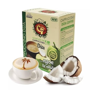 Puede incluir: Una caja de mezcla de café instantáneo con sabor a coco. La caja es amarilla y verde con una imagen de un coco y una taza de café. El texto en la caja dice "Cappuccino Dừa Coffee" y "...ngon tự nhiên".