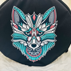 Peut inclure: Sac rond noir avec un motif de loup géométrique en turquoise, blanc et rose.