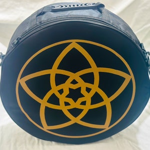 May include: Black round bag with a zipper closure and a gold starburst design on the front.