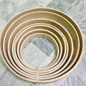 May include: A set of five wooden hoops, nested inside each other, with a natural wood finish. The hoops are of varying sizes, creating a visually appealing pattern.