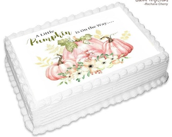 May include: A white cake with a pink and green edible image of pumpkins and flowers. The text "A Little Pumpkin is On the Way..." is printed on the image.