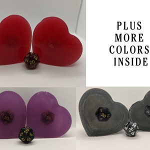 Puede incluir: Dos jaboneras en forma de corazón rojo con un dado negro de 20 caras en el centro. PLUS MÁS COLORES EN EL INTERIOR.