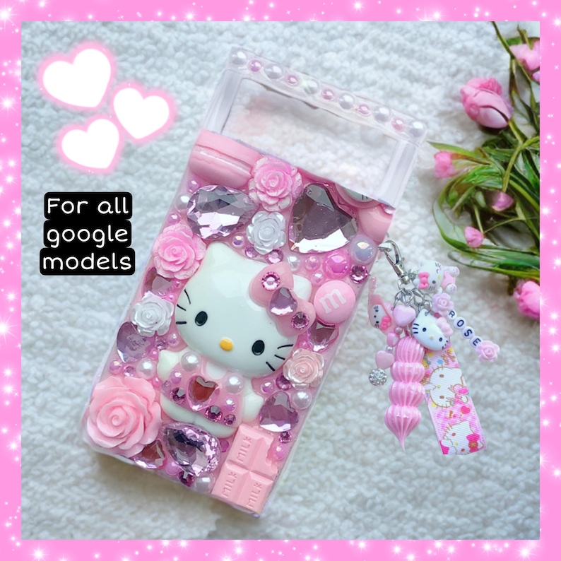 May include: A pink and white Hello Kitty phone case with rhinestones, flowers, and a pink and white Hello Kitty charm. The case is decorated with a pink and white Hello Kitty charm and the text "For all google models".