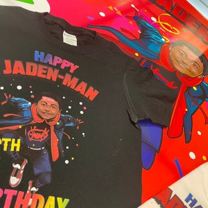 May include: Black t-shirt with a colorful graphic of a child dressed as Spiderman. The graphic includes the text "Happy Jaden-Man 6th Birthday".