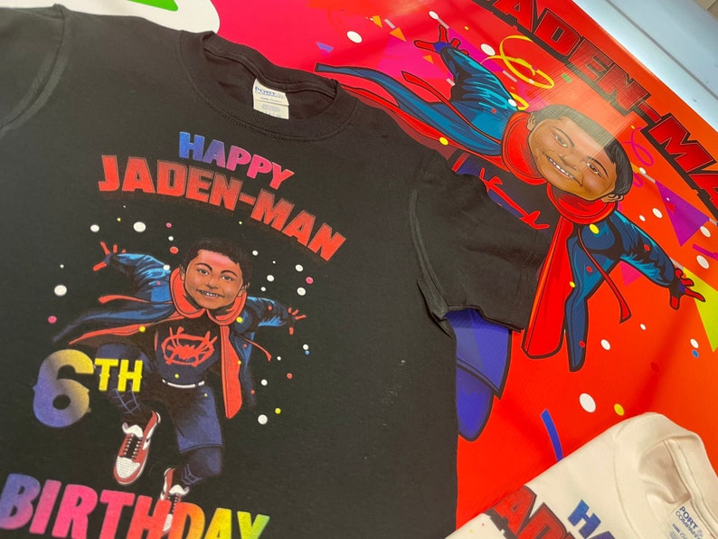 May include: Black t-shirt with a colorful graphic of a child dressed as Spiderman. The graphic includes the text "Happy Jaden-Man 6th Birthday".