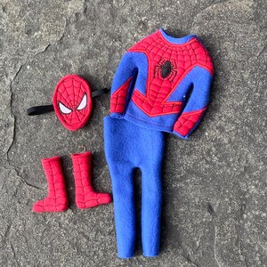 May include: A Spider-Man costume set, featuring a blue and red top with a spider emblem, matching blue pants, red boots, and a red mask with white eye details. The costume is made of soft fabric.