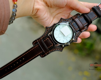 May include: A brown leather watch strap with orange stitching. The strap is designed to fit around the wrist and has a buckle closure.