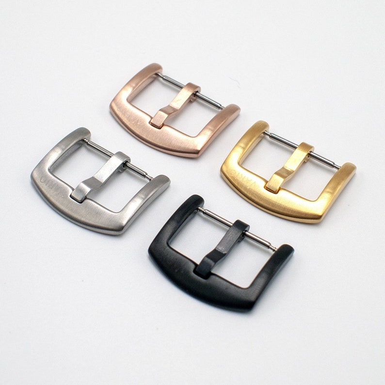 May include: Four watch band buckles in different finishes: silver, rose gold, gold, and black.