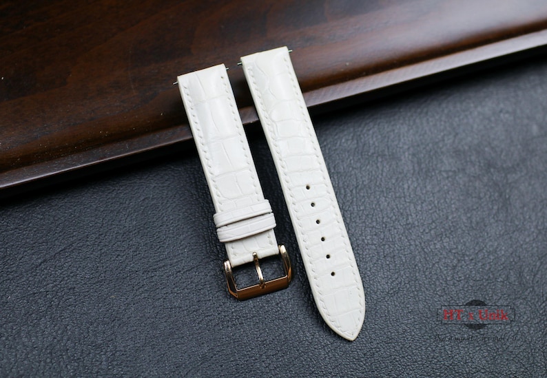 May include: Two white leather watch straps with gold buckles. The straps have a crocodile pattern.